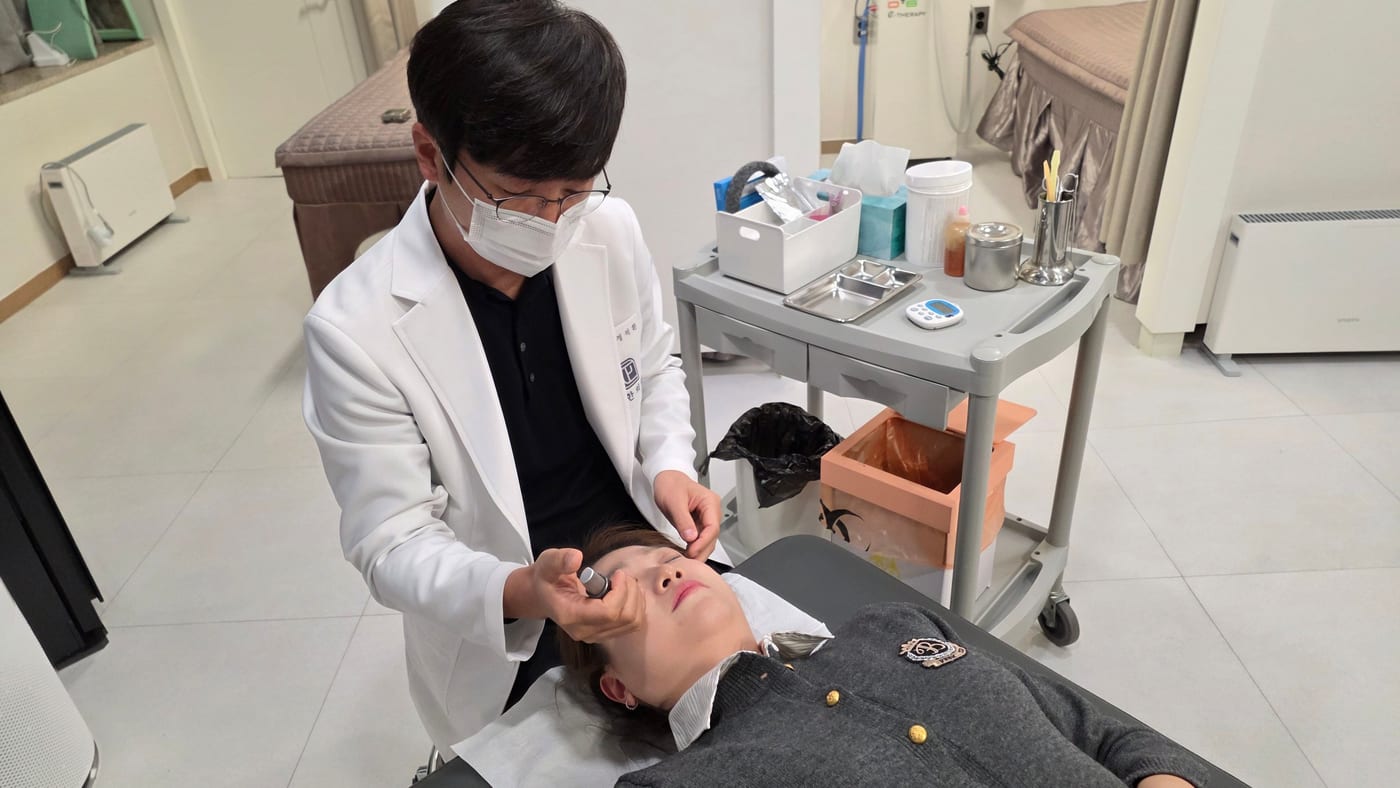 누워 있는 환자의 턱관절 주변 근육을 치료하는 정석환 원장